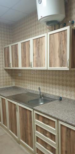 uma cozinha com um lavatório e armários de madeira em HOUSE IN AL AIN - 4 em Al Ain
