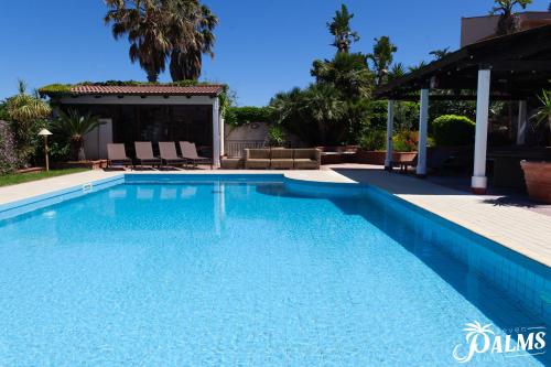 a swimming pool with blue water in a yard at Villa Seven Palms in Isola delle Femmine