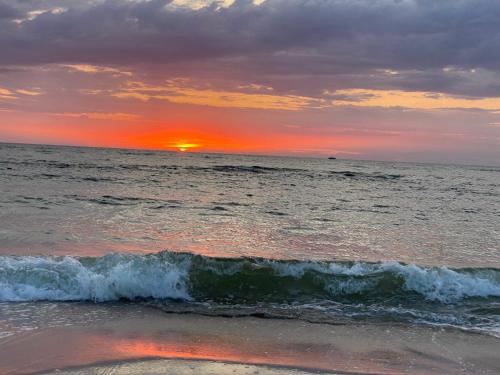 a sunset on the beach with the ocean at Apartament Nocuj w Rowach in Rowy
