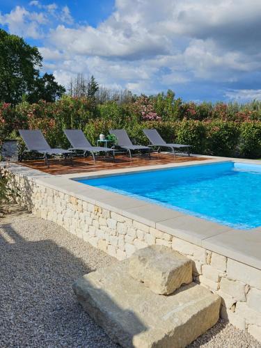 - une piscine avec des chaises longues à côté d'un mur en pierre dans l'établissement Gîte entier en Campagne, à Pernes-les-Fontaines