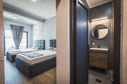 two beds in a room with a mirror and a sink at Sofia Luxury Apartments in Gevgelija