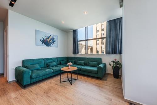 a living room with a green couch and a table at Marina Luxury Suites by PS in Durrës