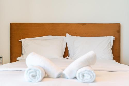 a bed with white sheets and white pillows at Marina Luxury Suites by PS in Durrës