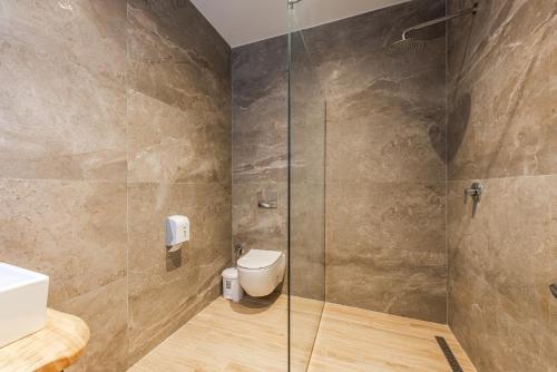 a bathroom with a toilet and a glass shower at Marina Luxury Suites by PS in Durrës