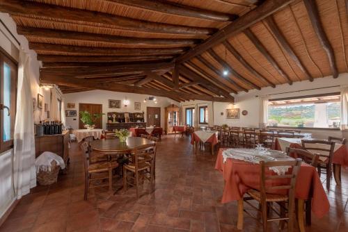 Un restaurante con techos de madera y mesas y sillas. en Tenuta Don Ballore Country Resort, en Galtellì