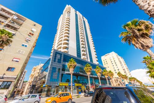 a tall building on a city street with palm trees at Marina Luxury Suites by PS in Durrës