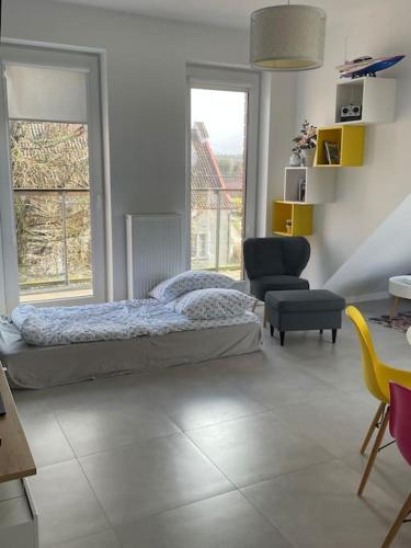 a bedroom with a bed and a chair and windows at Apartament z widokiem na jezioro in Rydzewo