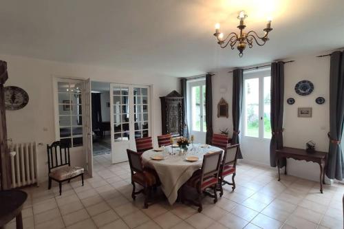 une salle à manger avec une table, des chaises et un lustre dans l'établissement Charmant 110m2 avec jardin privé, à Maisons-Laffitte