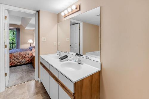 a bathroom with a sink and a mirror and a bed at Park Place Condos in Gatlinburg