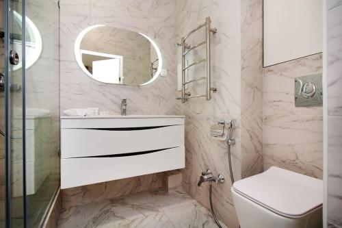 un bagno con lavandino, WC e specchio di Forum Residence a Almaty