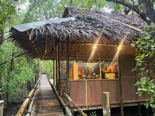 a small building with a bamboo roof and a walkway at Lekker Gezellig Dive Resort Manado in Bunaken