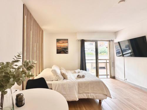une chambre blanche avec un lit et une table dans l'établissement Évasion Cannes : Baignoire spa, AC, Wifi, Netflix, à Cannes