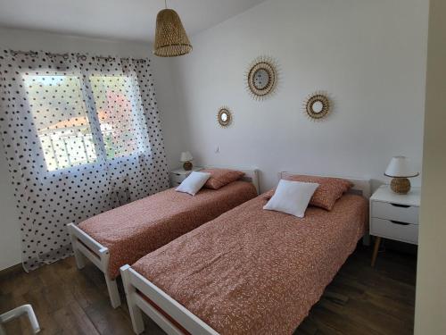 two beds in a small room with a window at Maison au calme proche océan in Vielle-Saint-Girons