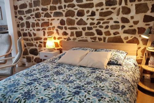une chambre avec un lit avec un mur en pierre dans l'établissement Studio chaleureux 5 mns chaine des Puys, à Saint-Genès-Champanelle