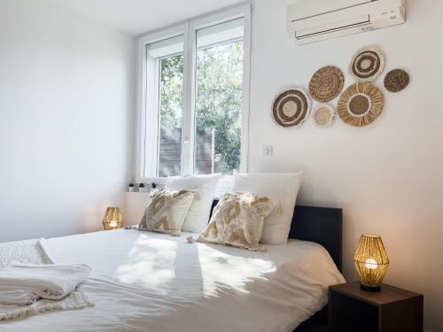 une chambre avec un lit blanc avec des oreillers et une fenêtre dans l'établissement Ste Marguerite élégant T2 avec terrasse, à Marseille