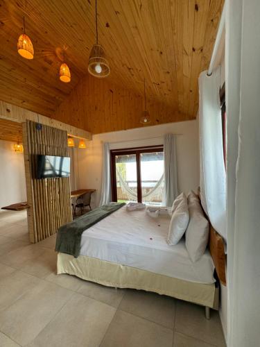 1 dormitorio con cama grande en el techo de madera en Pousada Corais do Bitingui en Japaratinga