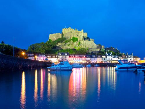 a castle on top of a hill with boats in the water at Gorey retreat main house in Gorey