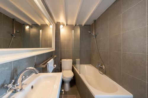 une salle de bain avec un lavabo, des toilettes et une baignoire dans l'établissement Geranimus 36B : Hearth of Paris, à Paris