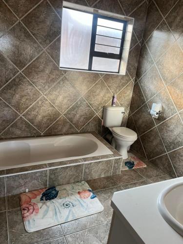 a bathroom with a tub and a toilet and a sink at Su Casa Port Alfred in Port Alfred