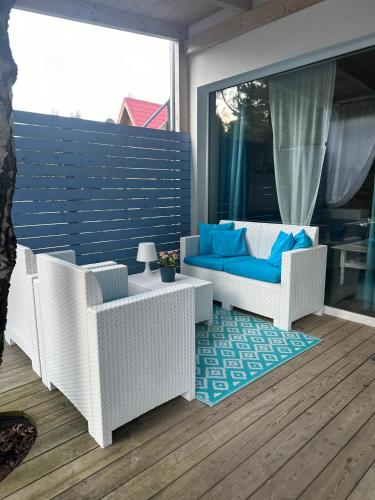 a patio with white wicker chairs and a blue couch at Zagroda Dębki in Dębki