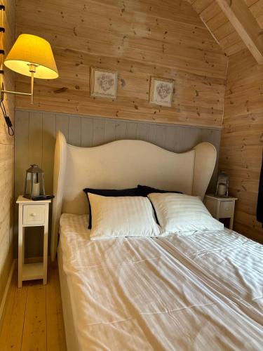 a bedroom with a large white bed with wooden walls at Zagroda Dębki in Dębki