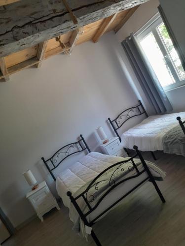 deux lits dans une chambre avec deux fenêtres dans l'établissement maison de campagne rénovée, à Duras