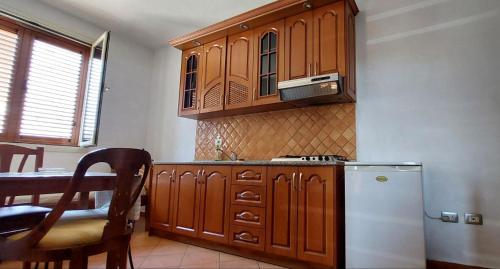 a kitchen with wooden cabinets and a white refrigerator at Iliria Durres Apartments in Durrës