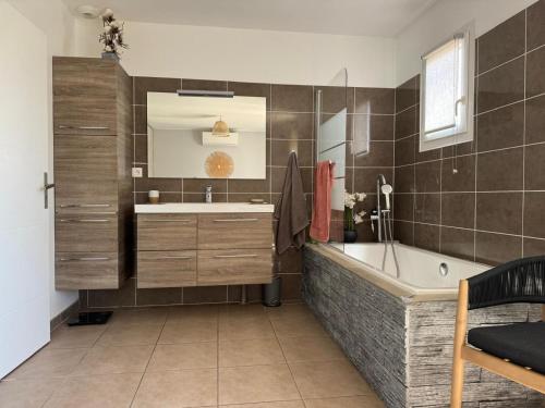 une salle de bain avec une baignoire, un lavabo et un miroir dans l'établissement Maison de vacances plein de charme avec piscine, à Mirepeisset