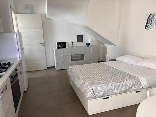 a white bedroom with a bed and a kitchen at 18 Gradi Apartments in Marsala