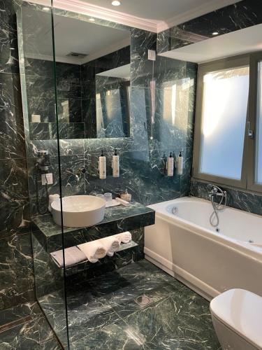 a bathroom with a tub and a sink and a bath tub at Aesthesis Arxontiko Luxury Rooms in Mirina