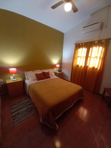 a bedroom with a bed and two lamps and a window at Cabañas Aromas Serranos in Alta Gracia