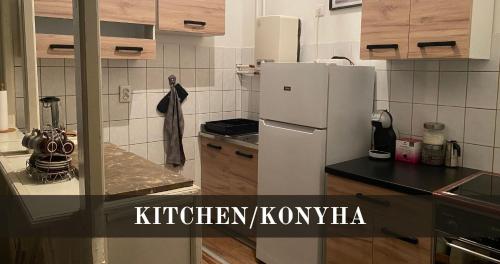 a kitchen with a white refrigerator and wooden cabinets at Bajcsy 6 Apartment in Debrecen
