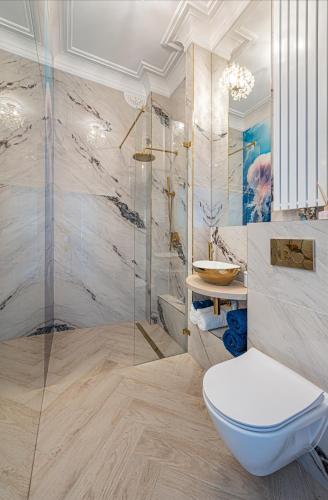 a bathroom with a toilet and a glass shower at Apartament Meduza Nadmorskie Miejsce in Gdynia