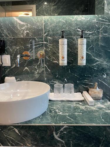 a bathroom with a sink and two bottles and glasses at Aesthesis Arxontiko Luxury Rooms in Mirina