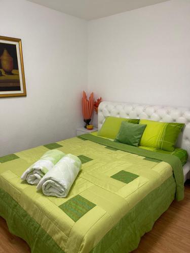 a bed with a green comforter and pillows on it at Apartman Dorotea in Trebinje