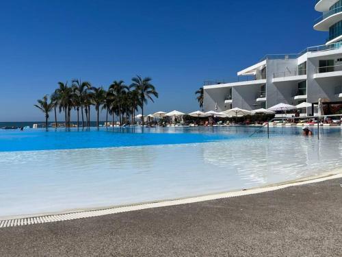 a large swimming pool with palm trees and umbrellas at Aria Ocean Playa Nuevo Vallarta in Nuevo Vallarta 