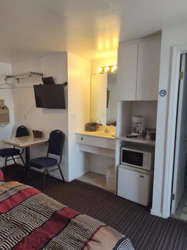 Una habitación con una cama y una cocina con una mesa. en Colorado Inn Motel, en Canon City