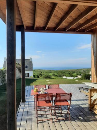 un patio avec une table et des chaises sur une terrasse dans l'établissement Maison en bois vue sur mer en Bretagne 5 couchages, à Plogoff
