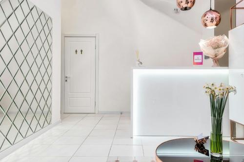 a white hallway with a table and vase of flowers at Cozy apartment with a beautiful view of old town in Tbilisi City