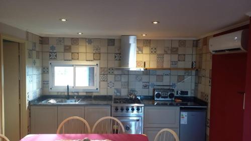 a kitchen with a stove and a sink and a table at Departamento Los Sauces in Macachín