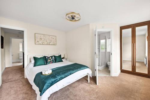 a bedroom with a large bed with green pillows at Radiant Retreat Ideal for LegoLand, Windsor, & LHR in Slough