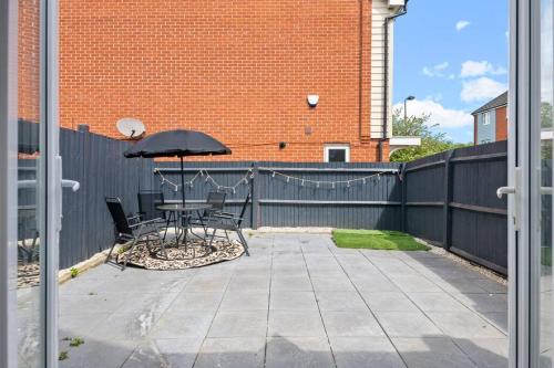 a patio with a table and an umbrella at Radiant Retreat Ideal for LegoLand, Windsor, & LHR in Slough