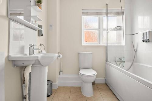 a white bathroom with a toilet and a sink at Radiant Retreat Ideal for LegoLand, Windsor, & LHR in Slough