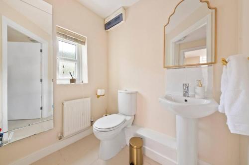 a white bathroom with a toilet and a sink at Radiant Retreat Ideal for LegoLand, Windsor, & LHR in Slough