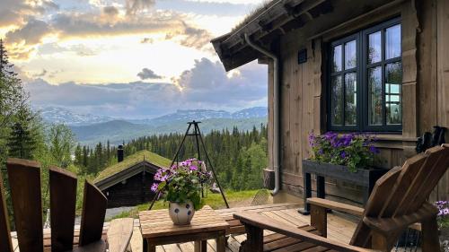 un porche con sillas y una mesa con flores. en Liaplassen Mountain Chalet - Beitostølen, en Beitostølen