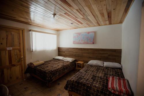 a bedroom with two beds and a wooden ceiling at Cabaña La Camelia in Creel