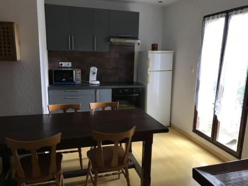 une cuisine avec une table, des chaises et un réfrigérateur dans l'établissement Logis cosy, à Montbéliard