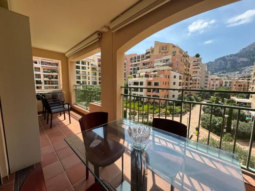 Elegant Monaco Port de Fontvieille apartment with Garden View and Pool Access في مونت كارلو: شرفة مع طاولة زجاجية وكراسي