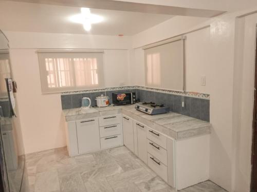 a kitchen with white cabinets and a counter top at La-Rivière Vacation Home in Lal-lo