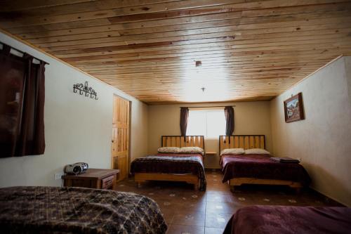 1 Schlafzimmer mit 2 Betten und Holzdecke in der Unterkunft Cabaña La Victoriana in Creel